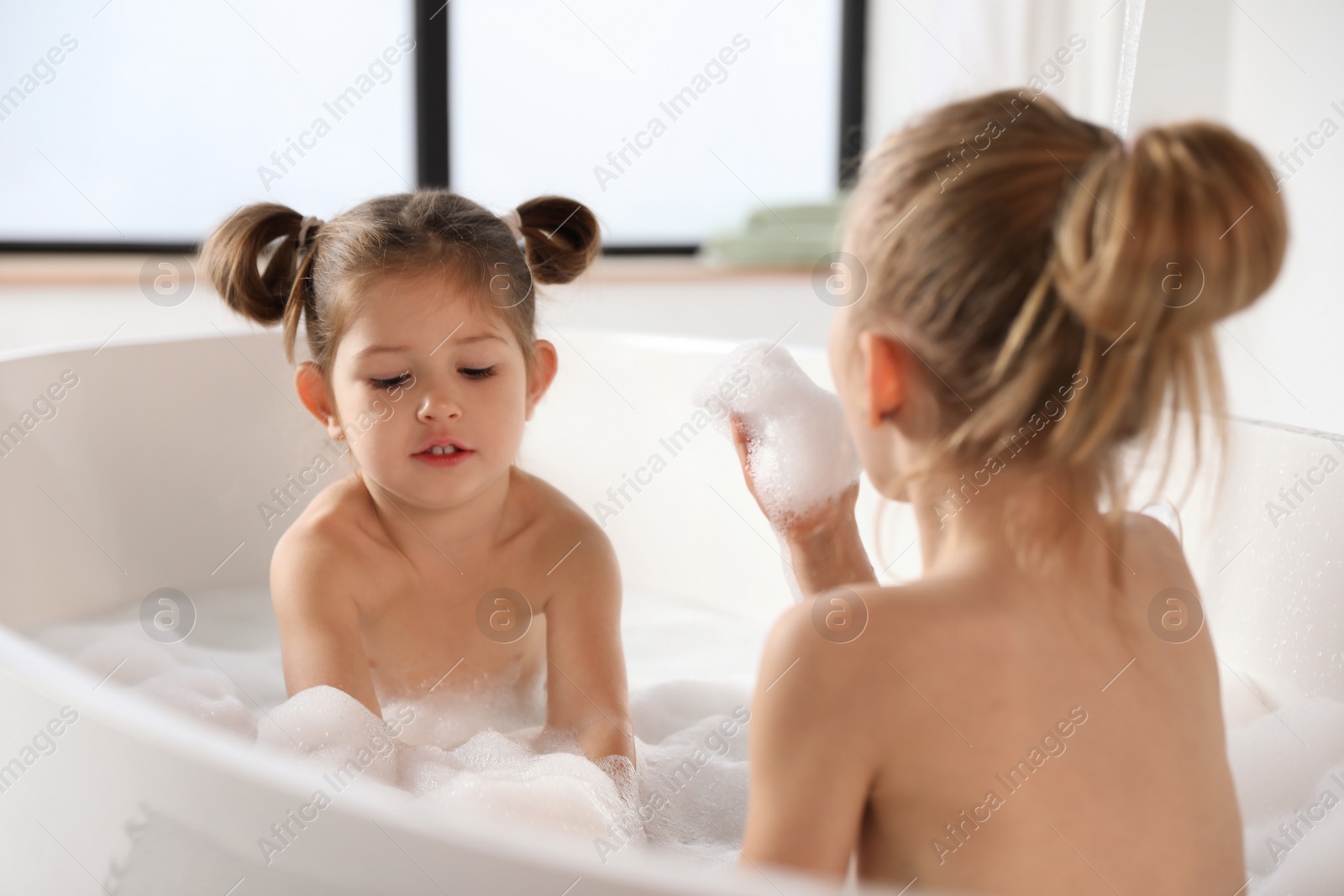 Photo of Cute little sisters taking bubble bath together