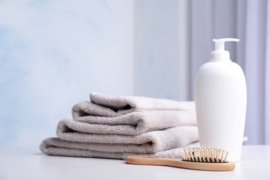 Photo of Bottle with shampoo, towels and brush on table