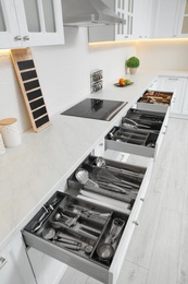 Open drawers with different utensils in kitchen