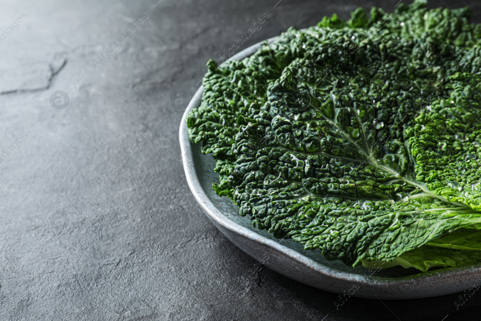 Photo of Fresh savoy cabbage leaves on black table, closeup. Space for text