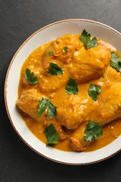 Photo of Tasty chicken curry with parsley on black textured table, top view