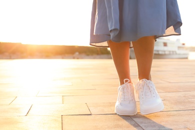 Photo of Young woman walking on pier at sunset light. Space for text