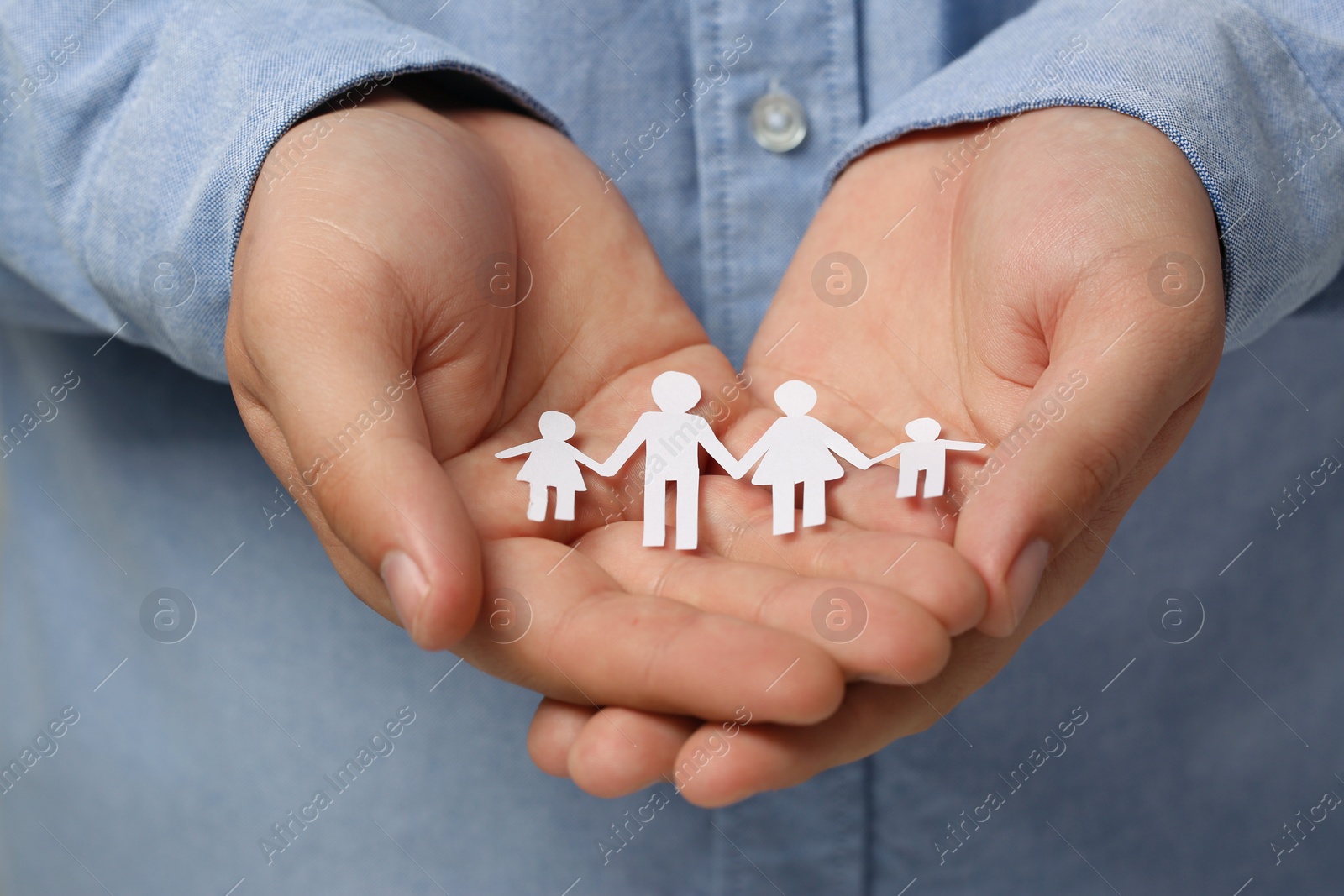 Photo of Man holding paper family figures, closeup. Insurance concept