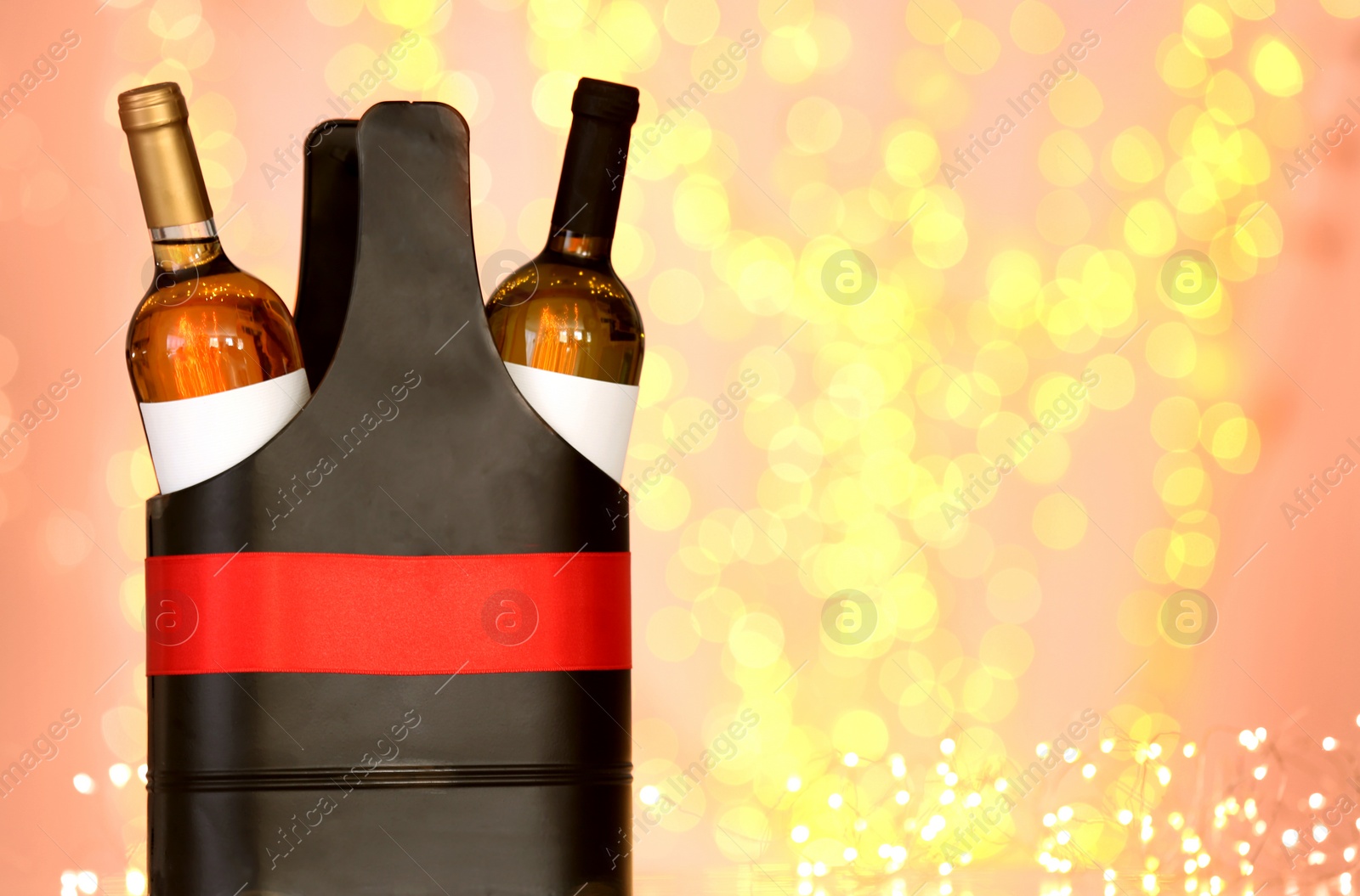 Photo of Festive package with bottles of wine against blurred lights. Space for text