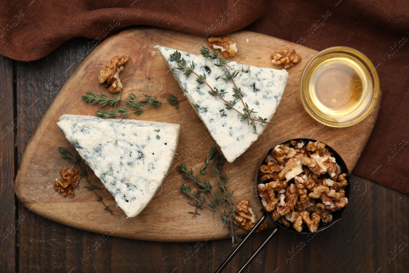 Photo of Tasty blue cheese with thyme, honey and walnuts on wooden table, top view