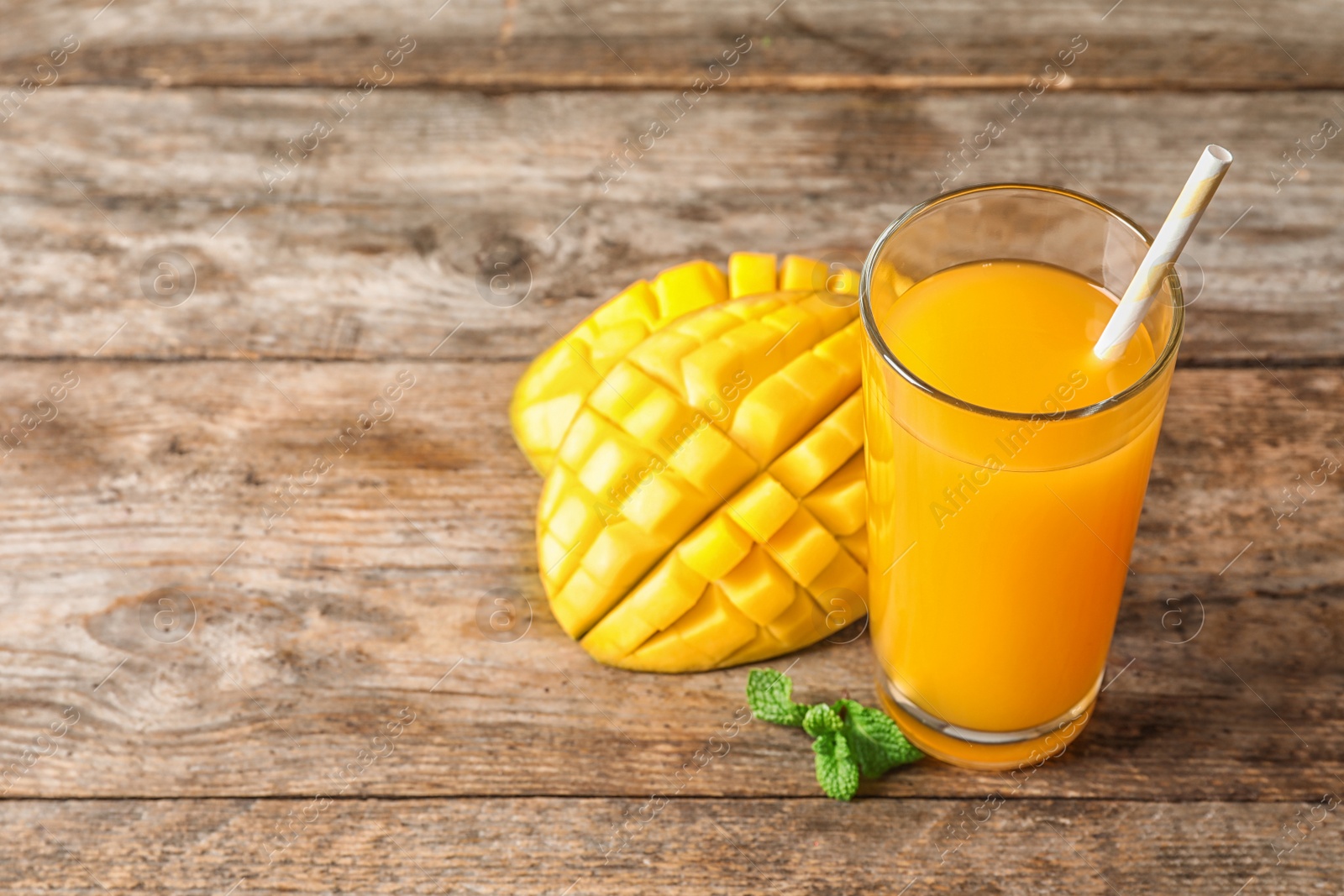 Photo of Fresh mango drink and cut fruit on wooden table. Space for text