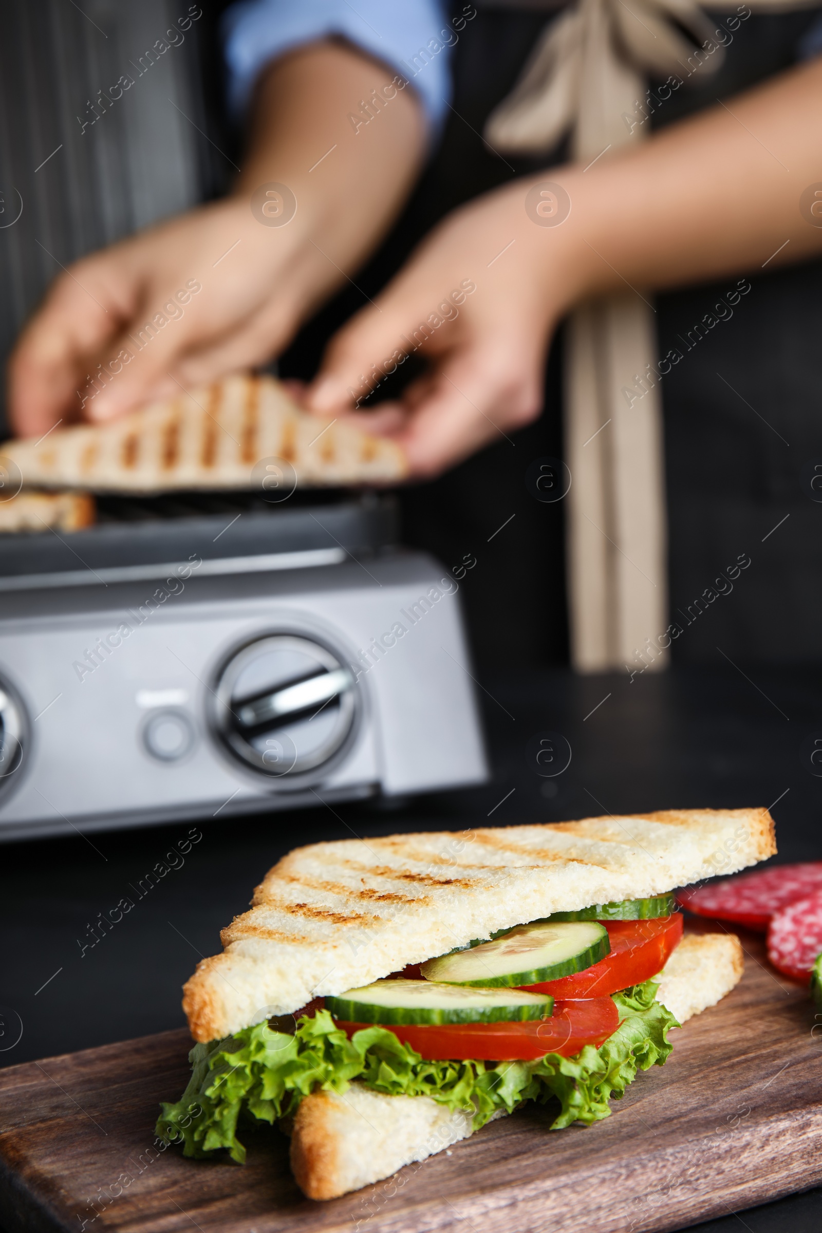 Photo of Tasty sandwich with tomato and cucumber on black table, closeup