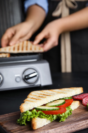 Photo of Tasty sandwich with tomato and cucumber on black table, closeup