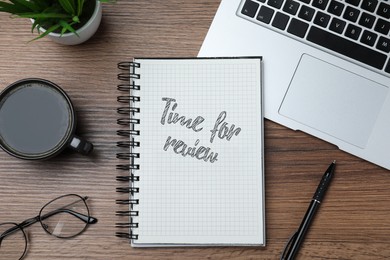 Image of Notepad with text Time For Review, pen, laptop and cup of coffee on wooden table, flat lay