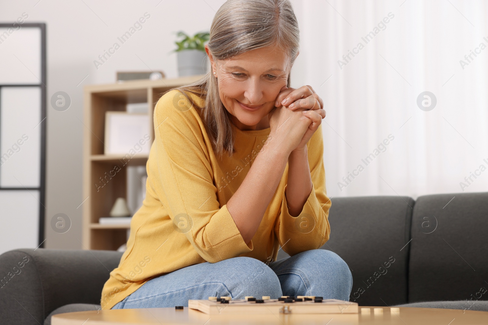 Photo of Thoughtful senior woman playing checkers at home