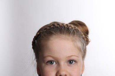 Little girl with braided hair on white background, closeup