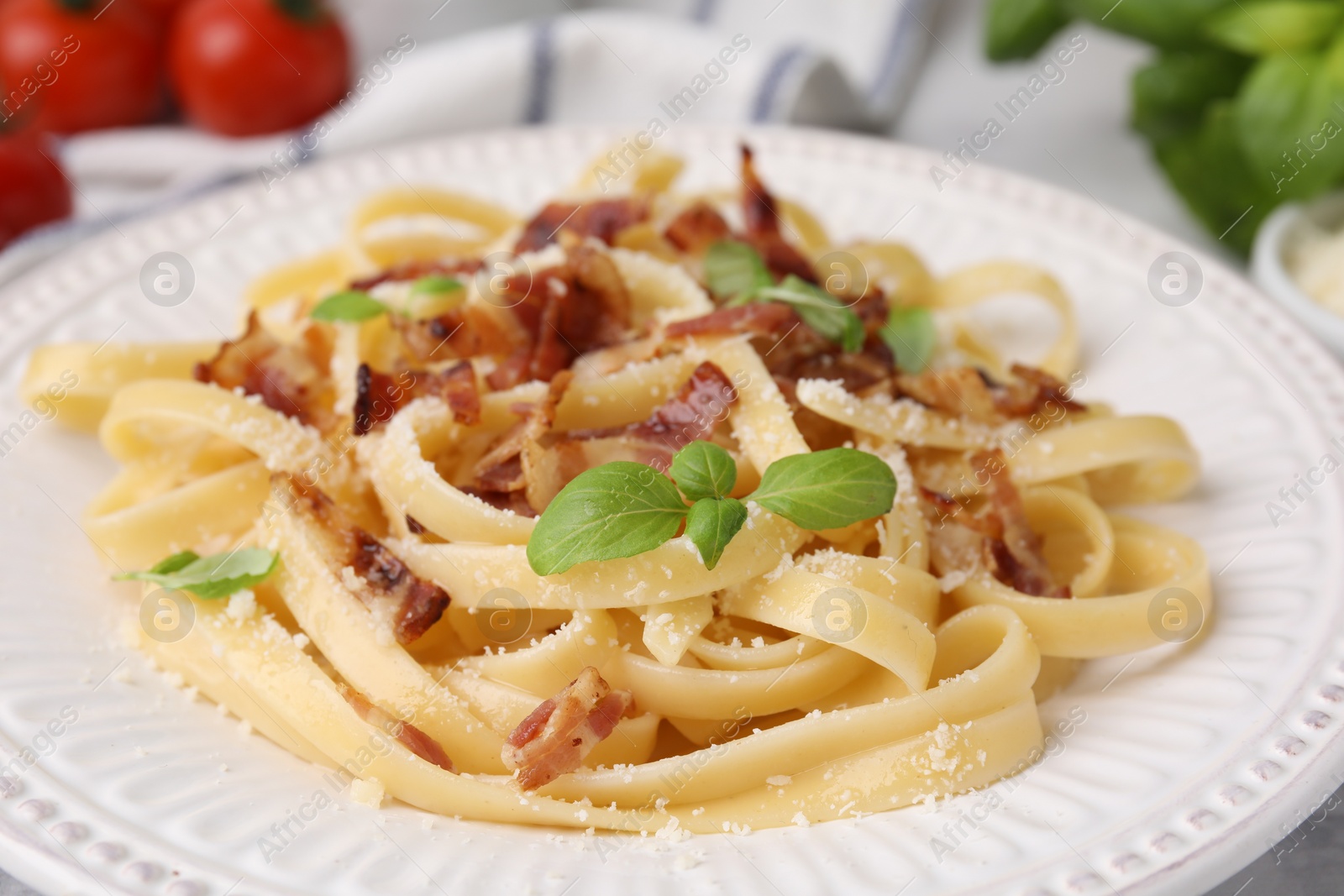 Photo of Tasty pasta with bacon and basil on table, closeup