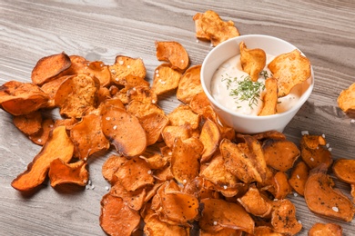 Photo of Sweet potato chips and bowl of sauce on wooden background