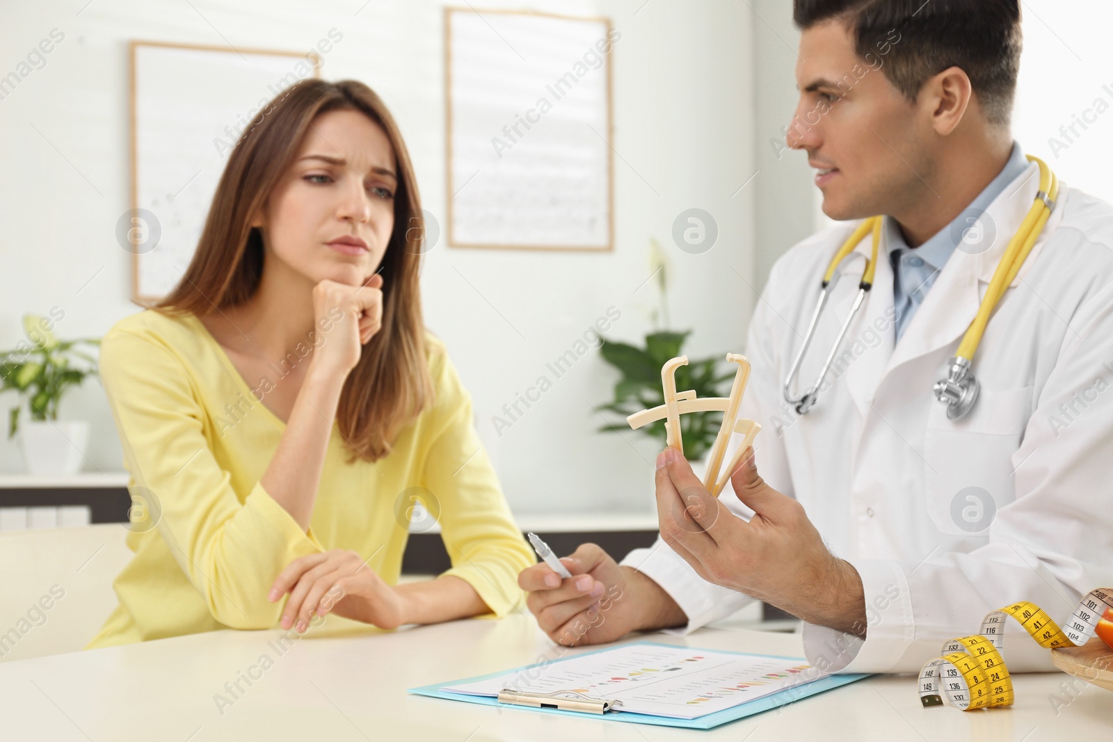 Photo of Nutritionist consulting patient at table in clinic, focus on hands