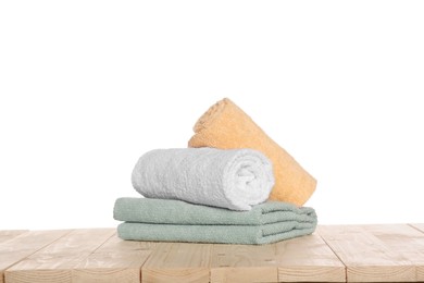 Photo of Soft colorful terry towels on wooden table against white background