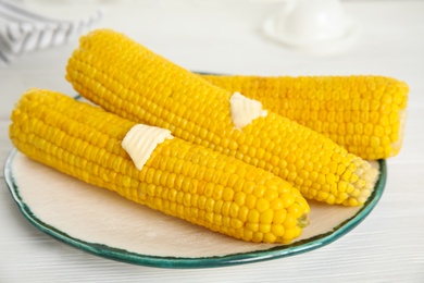 Fresh corn cobs with butter on white wooden table