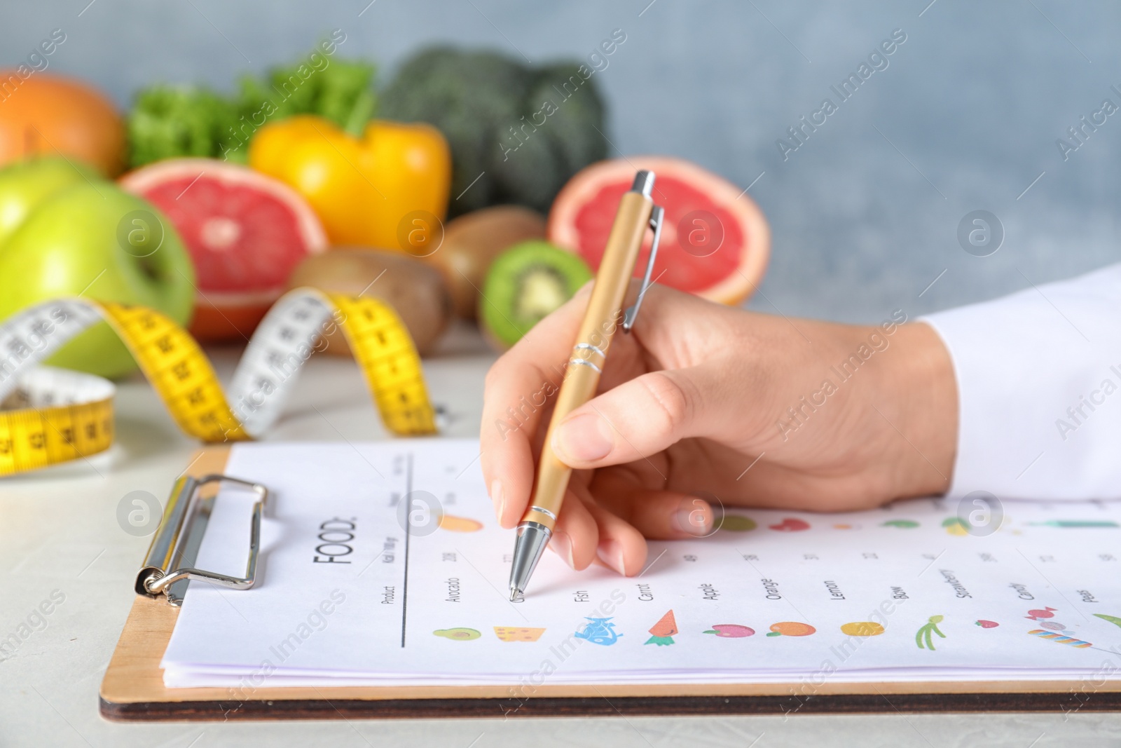 Photo of Female nutritionist with list of products at table, closeup