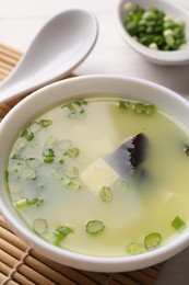Photo of Bowl of delicious miso soup with tofu served on table, closeup