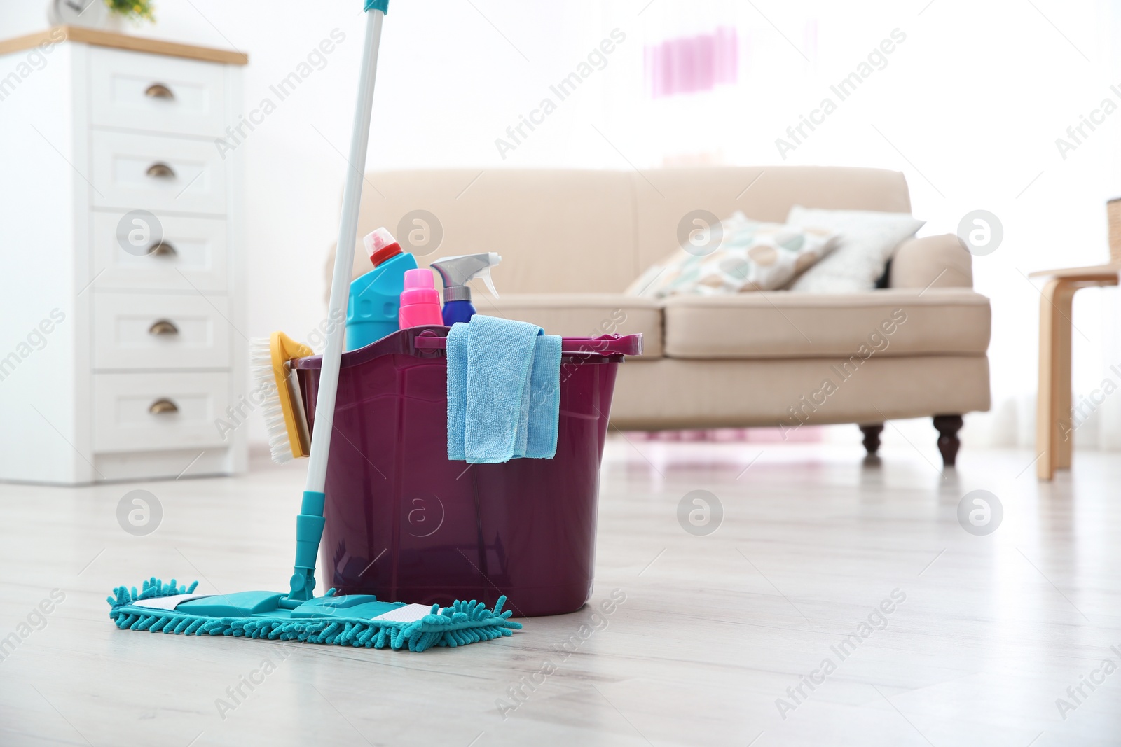 Photo of Mop and detergents on floor in living room, space for text. Cleaning service