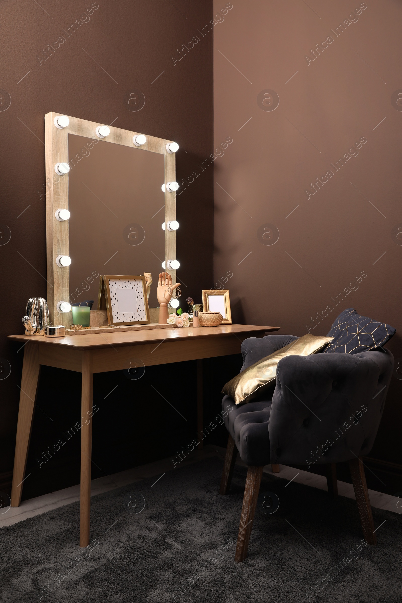 Photo of Stylish dressing table with mirror near brown wall in room