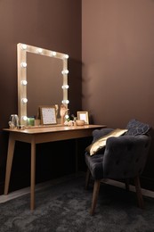 Photo of Stylish dressing table with mirror near brown wall in room