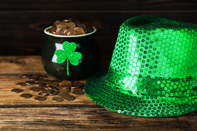 Green leprechaun hat and pot with gold coins on wooden table. St. Patrick's Day celebration