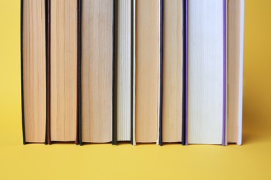 Collection of hardcover books on yellow background, closeup