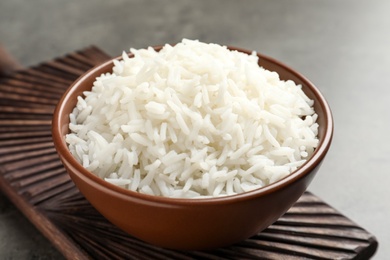 Photo of Bowl of tasty cooked white rice on grey table
