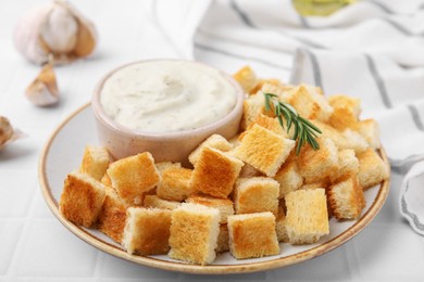 Photo of Delicious crispy croutons with rosemary and sauce on white table, closeup