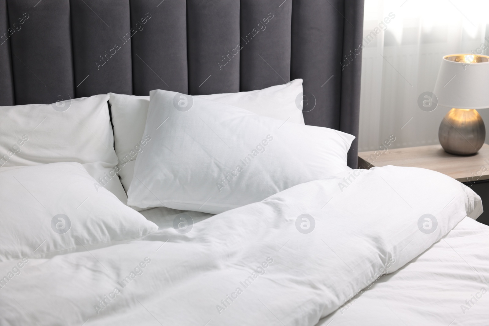 Photo of Soft white pillows and duvet on bed at home