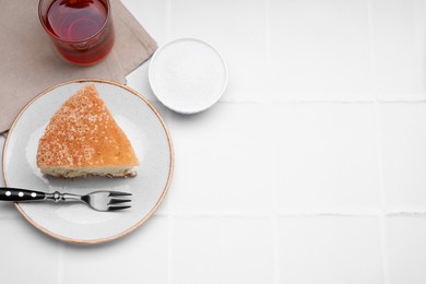 Piece of tasty sponge cake served on white tiled table, flat lay. Space for text
