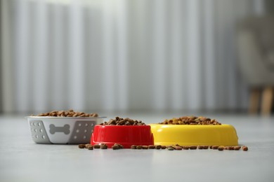 Photo of Dry food in pet bowls on floor indoors, space for text