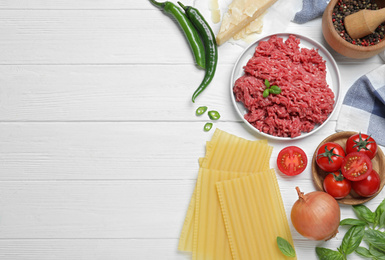 Photo of Fresh lasagna ingredients on white wooden table, flat lay. Space for text