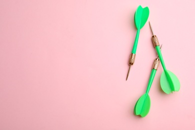 Photo of Green dart arrows on pink background, flat lay with space for text