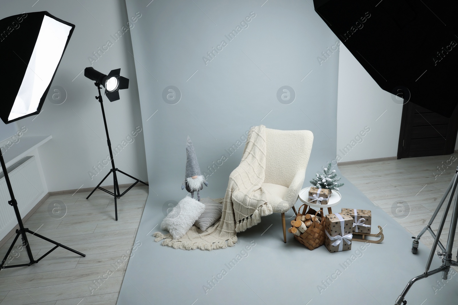 Photo of Stylish photo zone with armchair and Christmas decor in professional studio