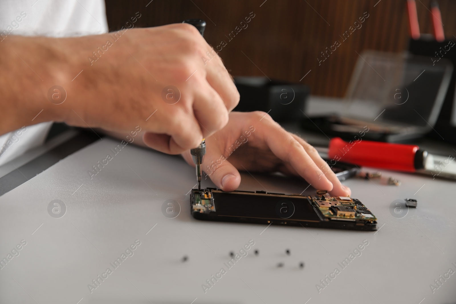 Photo of Technician repairing mobile phone at table, closeup