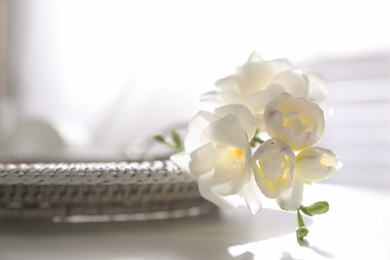 Photo of Beautiful freesia flowers on white table indoors, closeup