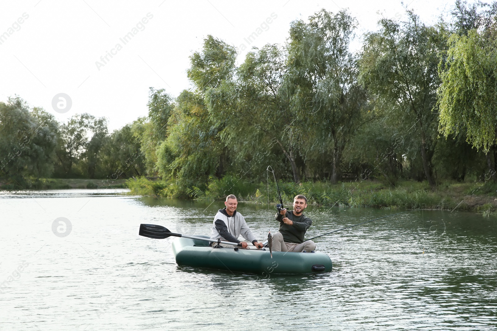 Photo of Friends fishing from boat on river. Recreational activity