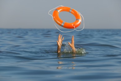 Image of Drowning woman with raised hands getting lifebelt in sea