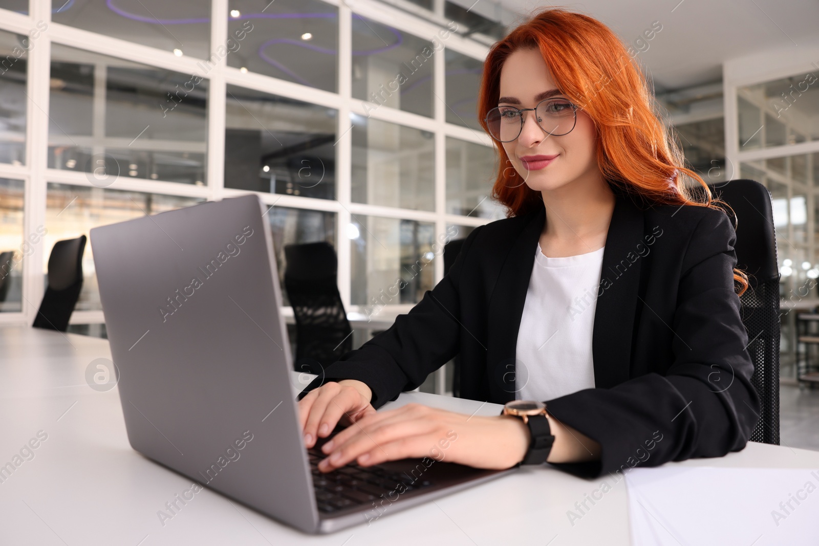 Photo of Woman working with laptop at white desk in office