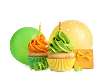 Delicious birthday cupcakes with candles, gift and balloons on white background