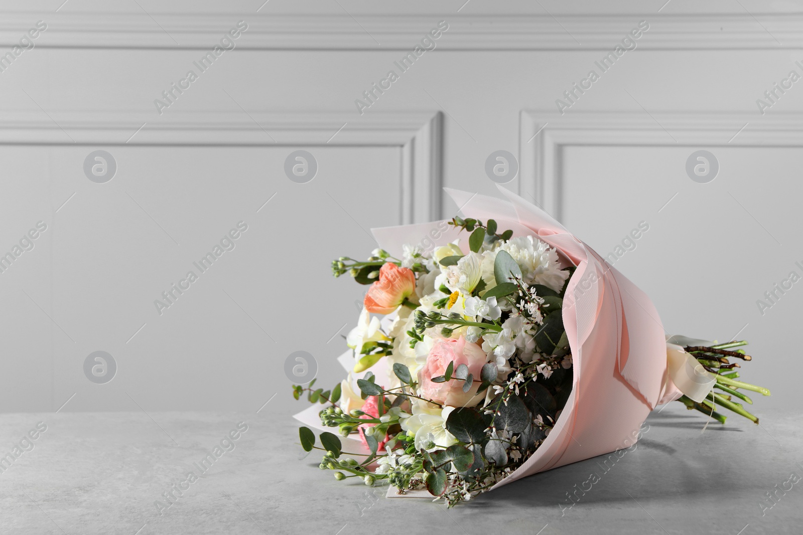 Photo of Bouquet of beautiful flowers on light grey table. Space for text