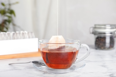 Photo of Brewing tea with bag in cup on table