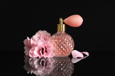 Vintage bottle of perfume and beautiful flowers on black background