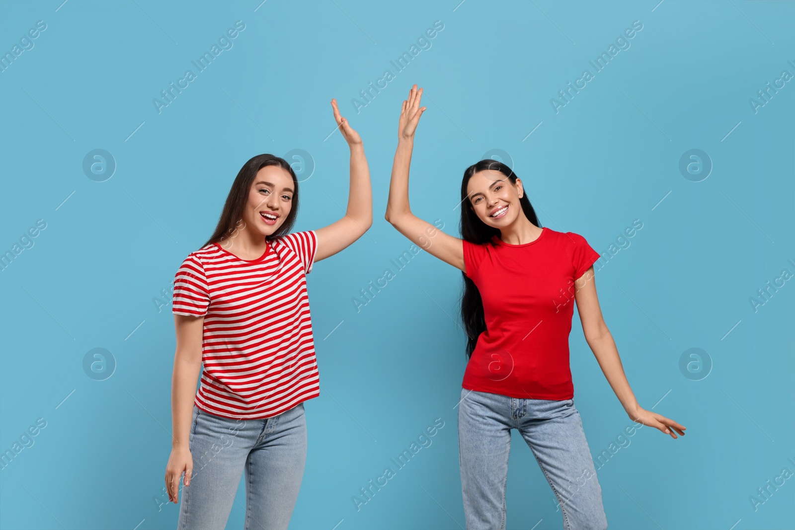 Photo of Women giving high five on light blue background