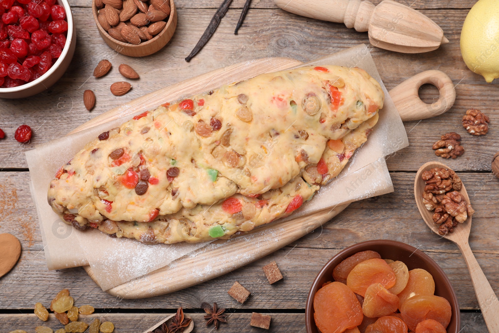 Photo of Unbaked Stollen with candied fruits and raisins on wooden table, flat lay