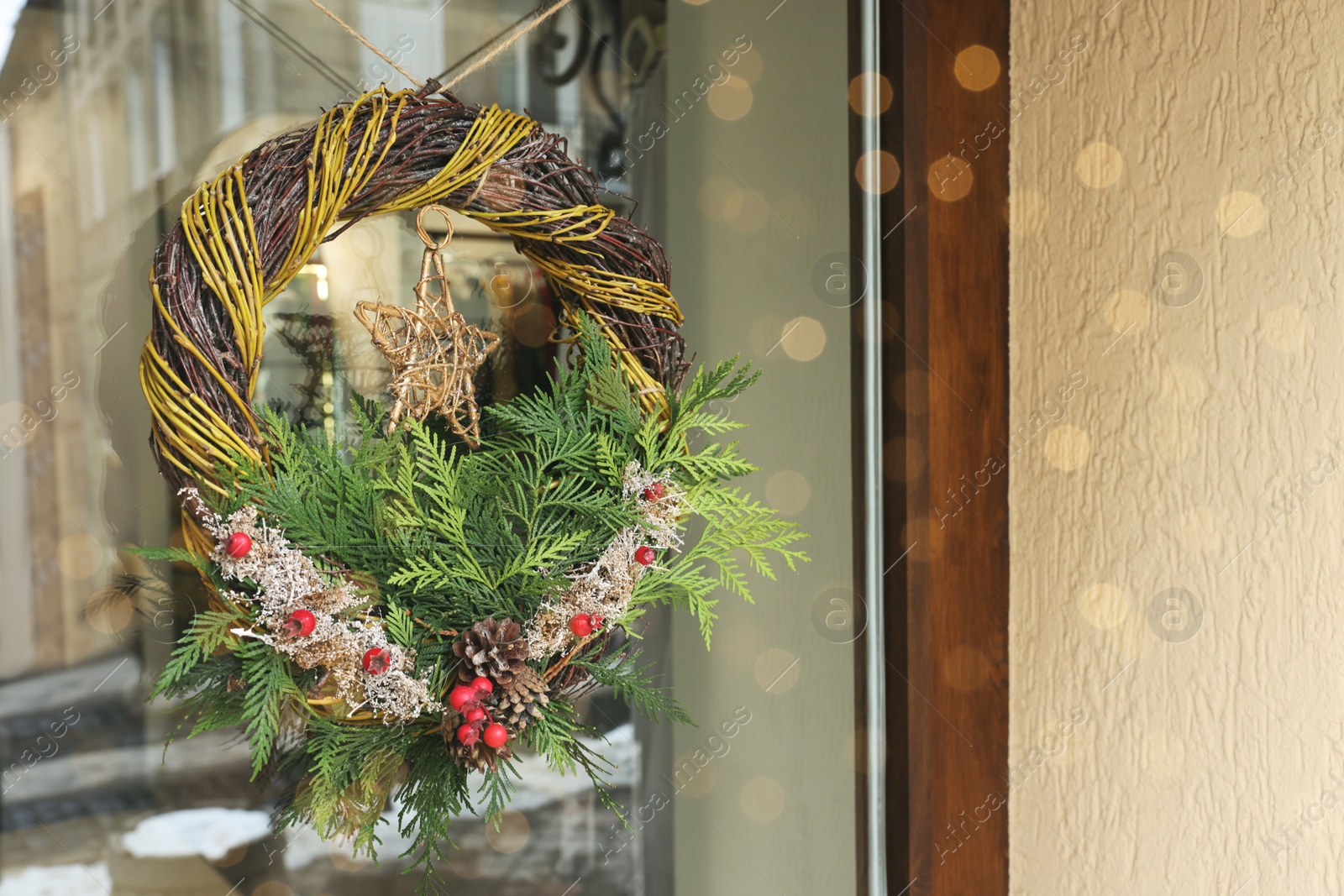Photo of Beautiful Christmas wreath hanging on glass door, space for text
