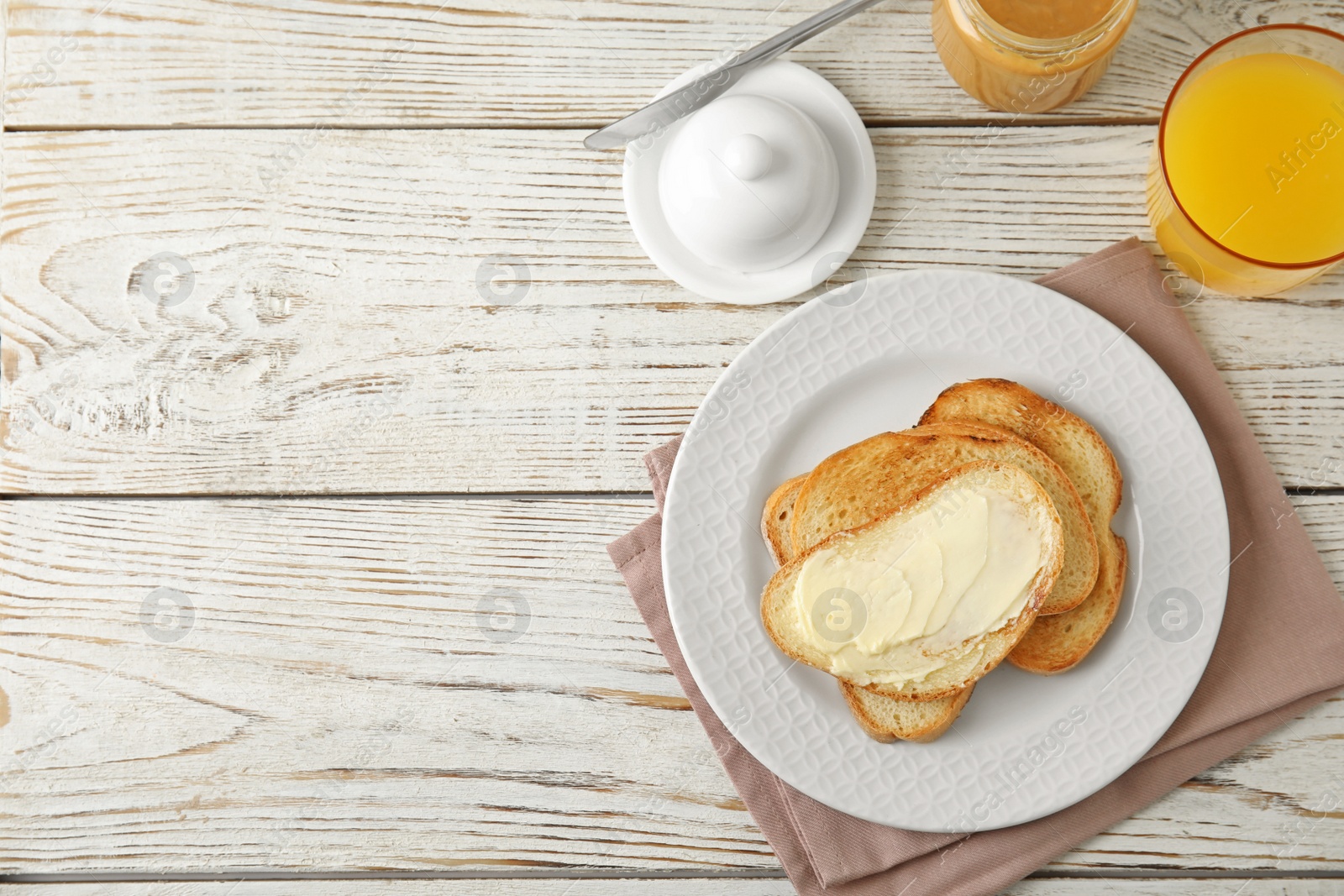 Photo of Tasty bread with butter served for breakfast on white wooden table, top view. Space for text