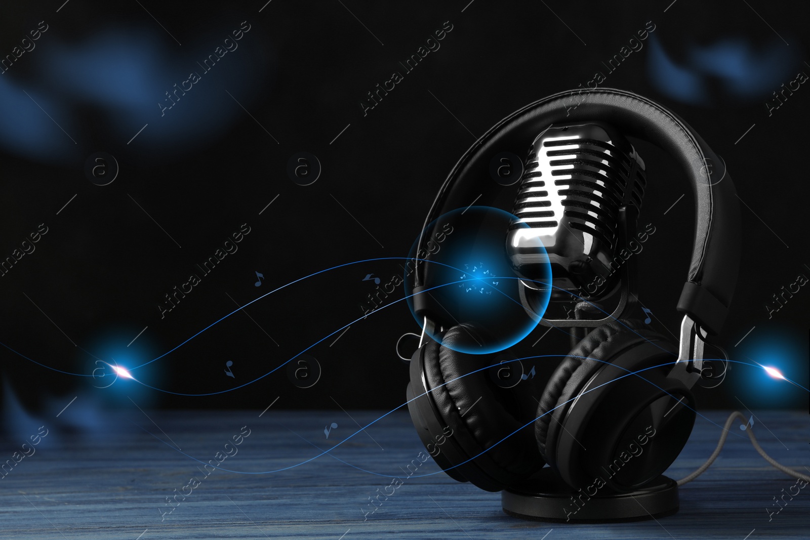 Image of Retro microphone and headphones with illustration musical notes on table against dark background. Space for text