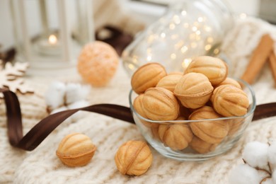 Photo of Delicious nut shaped cookies with boiled condensed milk and Christmas decor on knitted fabric. Space for text